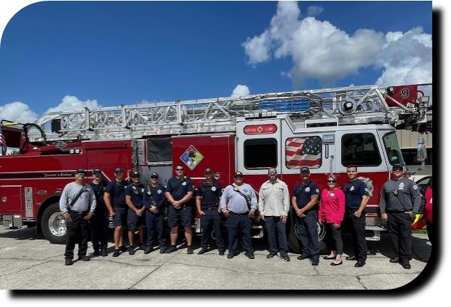 Group of firefighters standing in front of a fire truck.