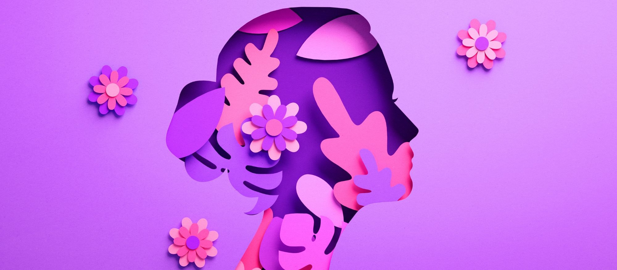 A paper art silhouette of a woman's face, adorned with colorful floral and leaf designs against a purple background.