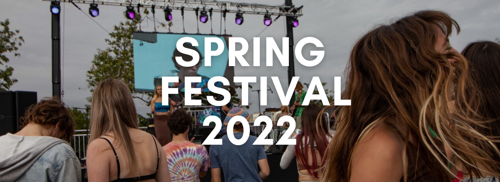 Crowd at an outdoor "Spring Festival 2022" event with stage lighting and a big screen in the background.