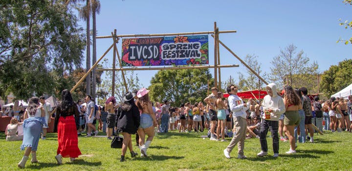 Outdoor spring festival with a crowd, food stands, and a sunny sky.