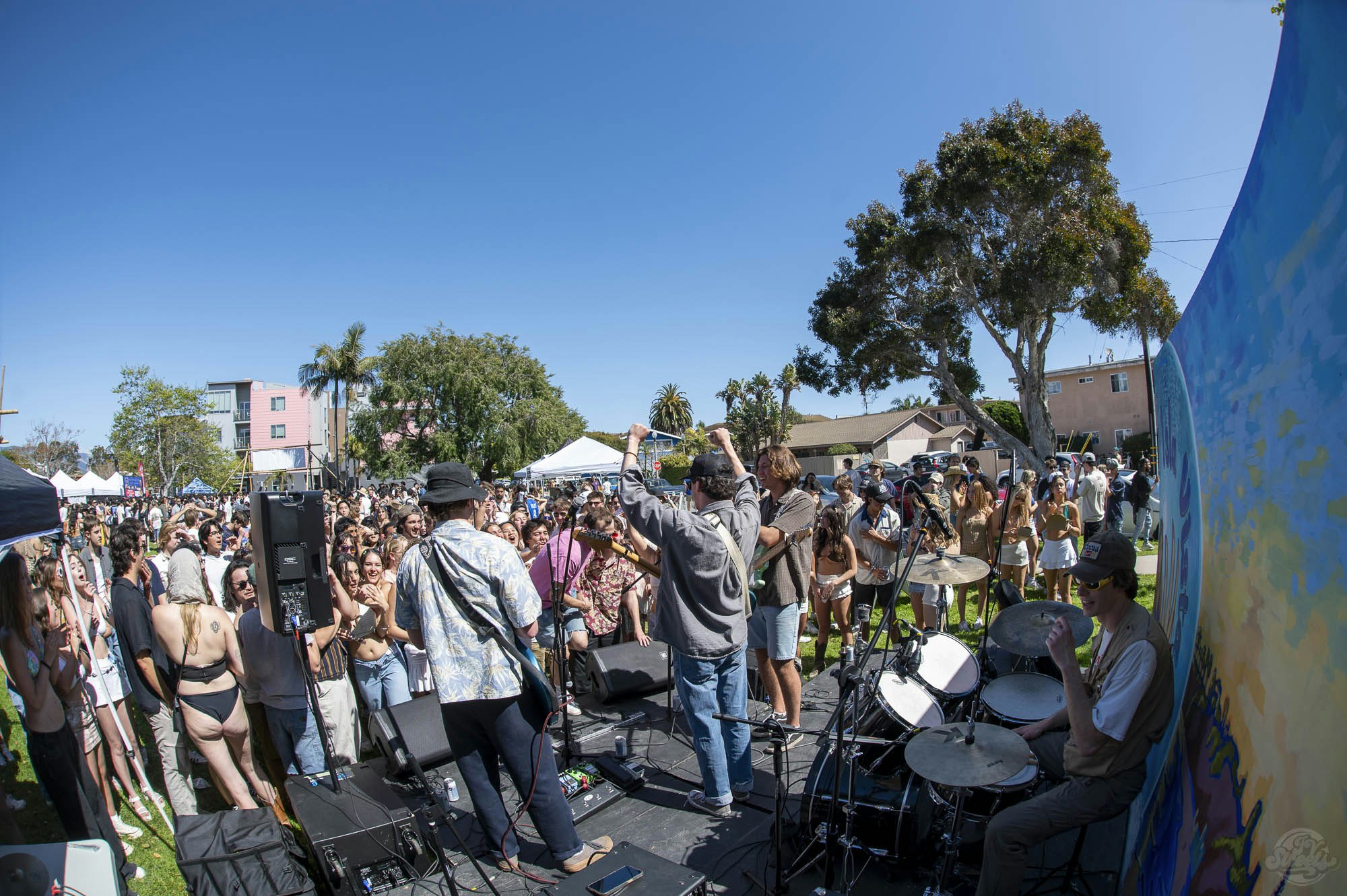 Outdoor concert with a band performing and an enthusiastic crowd enjoying the music.