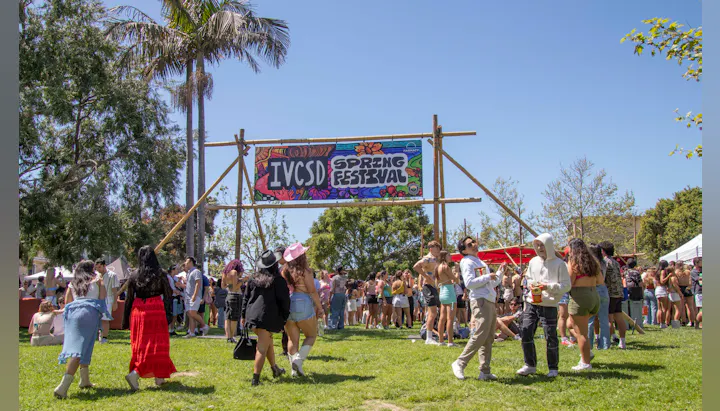 A vibrant outdoor scene at the IV CSD Spring Festival with crowds enjoying music, food, and festivities under a clear blue sky.