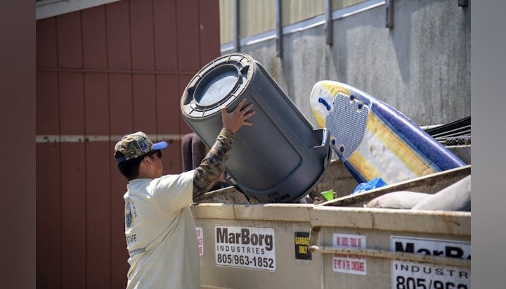 A person is emptying a trash can into a dumpster. There's visible text for "MarBorg Industries" with contact info.