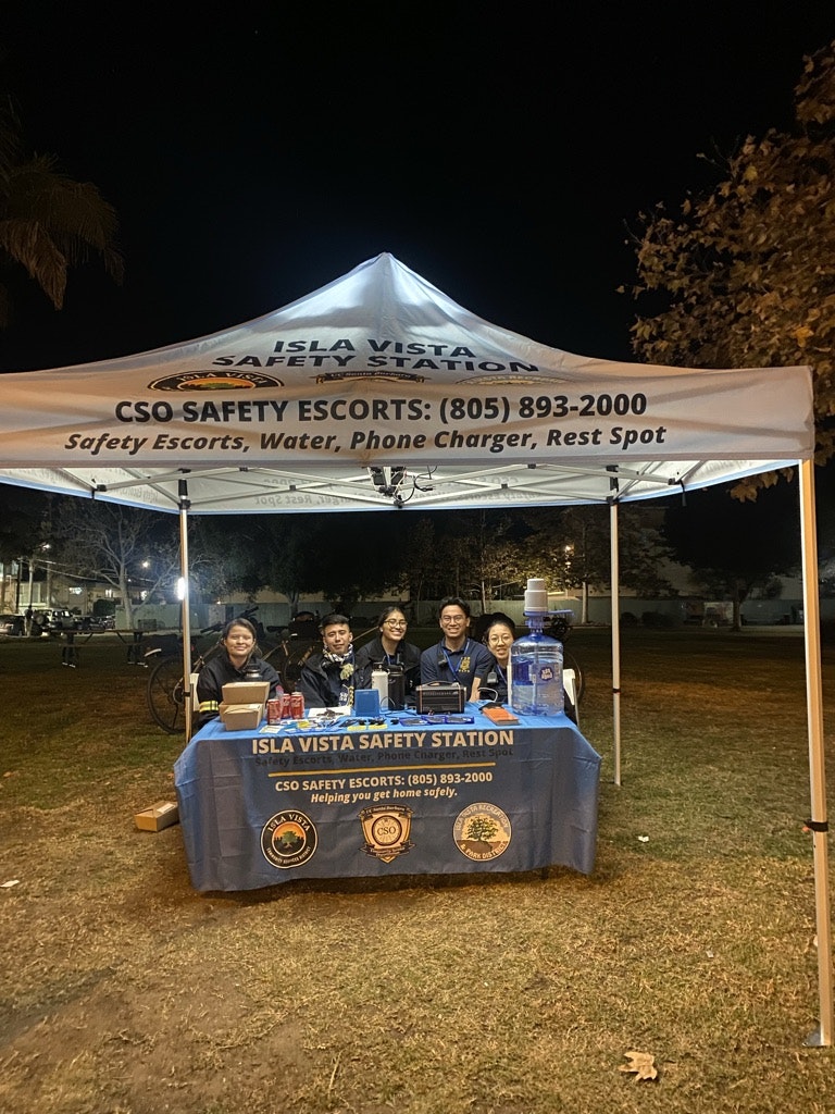 A group of people at the Isla Vista Safety Station providing services like safety escorts, water, phone charging, and a rest spot.