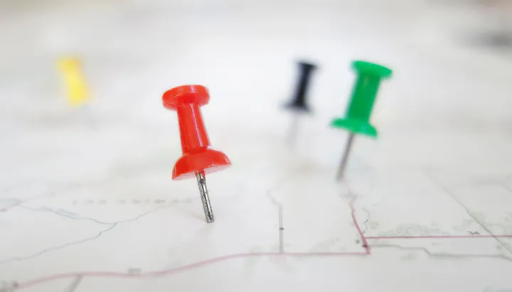 Colorful pushpins on a map, indicating locations.