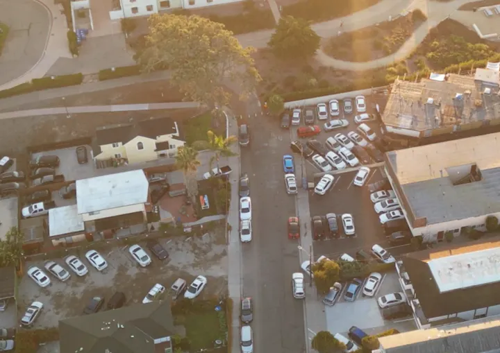 Aerial view of parked cars and buildings during sunset.