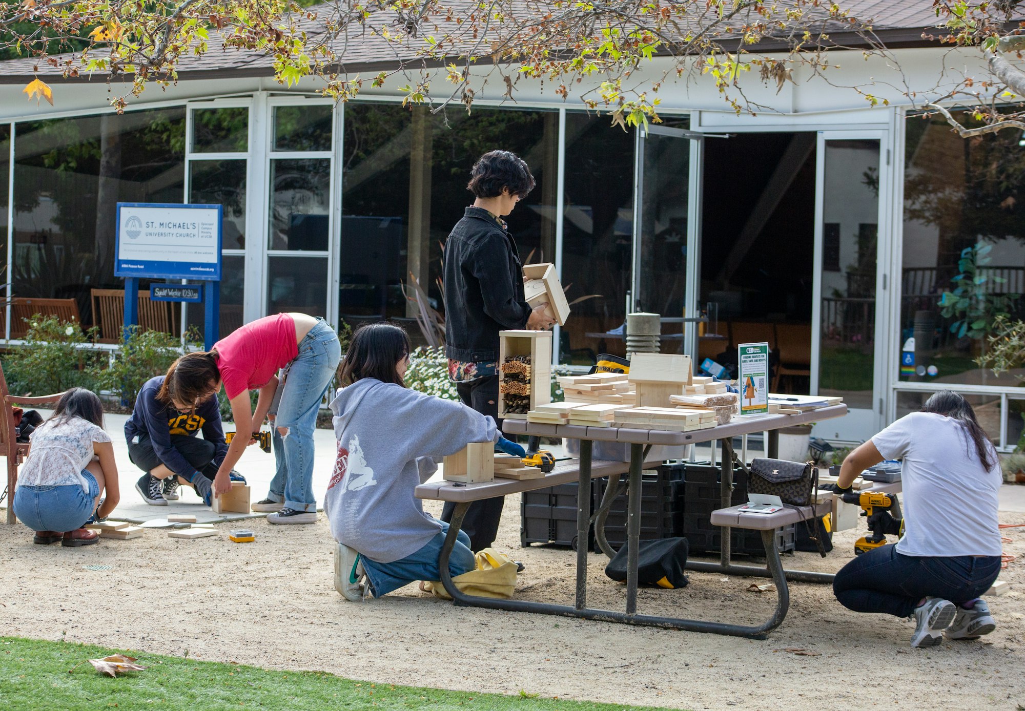 People building wooden structures outdoors near a church.