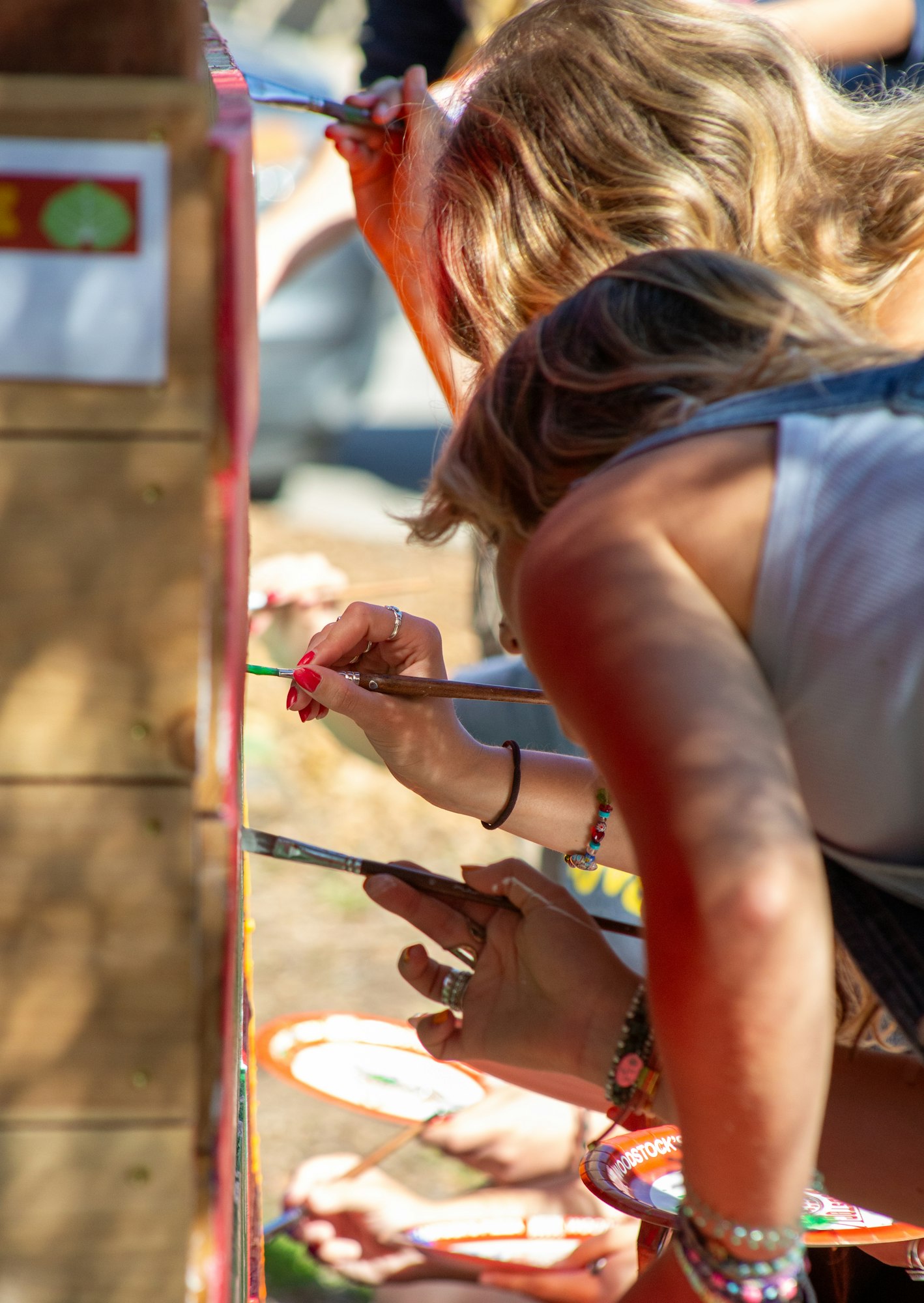 People painting on a vertical surface, focusing on brushstrokes and details.