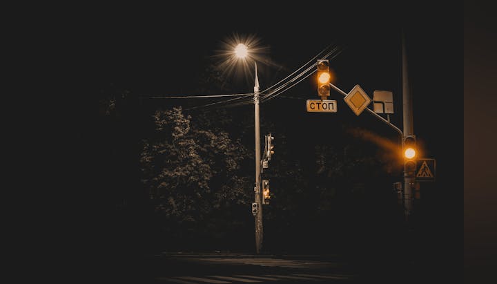 A nighttime view of a streetlight and illuminated traffic signals with Cyrillic stop sign.