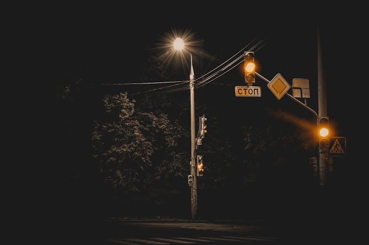 A nighttime view of a streetlight and illuminated traffic signals with Cyrillic stop sign.