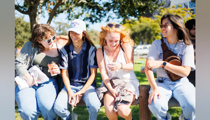 Group of young people laughing and sitting together outdoors.