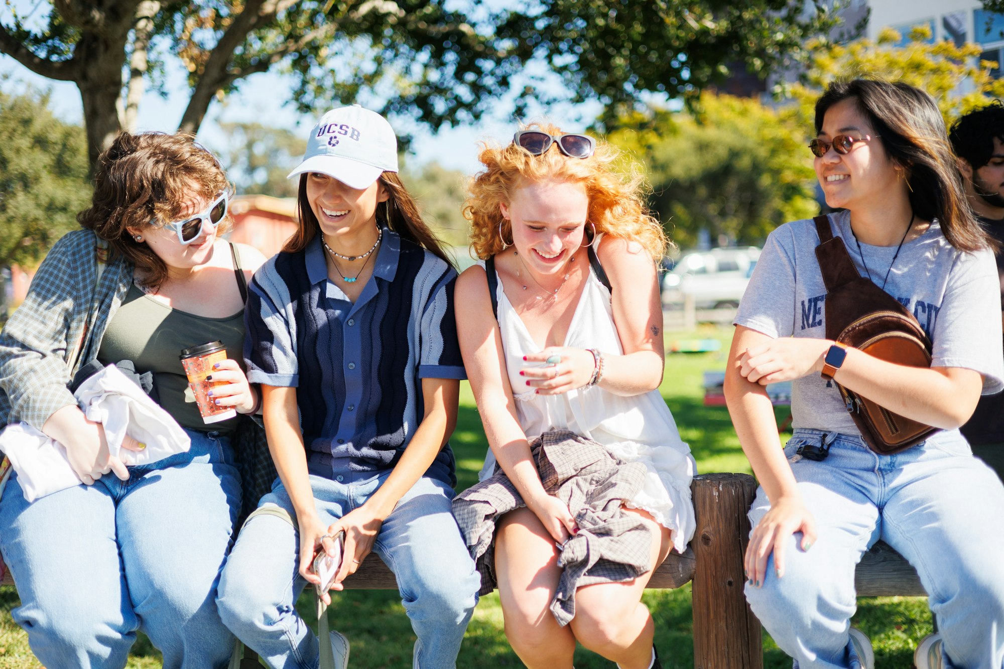 Group of young people laughing and sitting together outdoors.