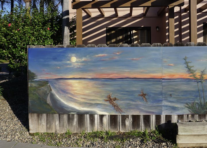 A beautiful mural depicting a serene beach scene at sunset with birds flying over the water.