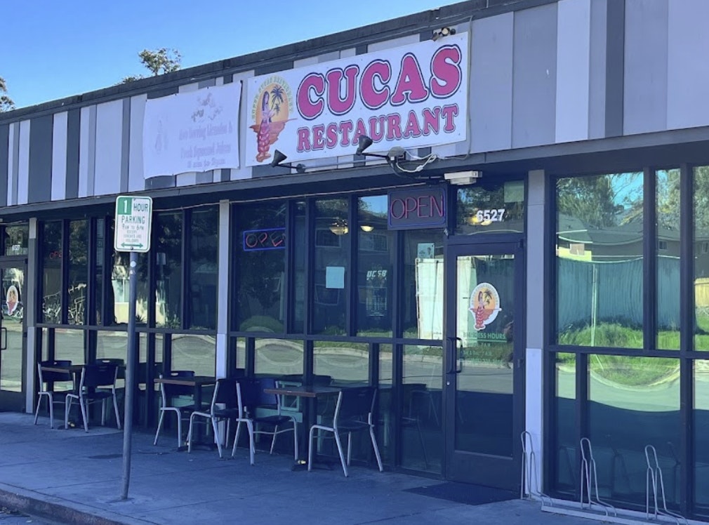 The image shows Cuca's Restaurant with an "Open" sign, outdoor seating, and a one-hour parking sign outside.