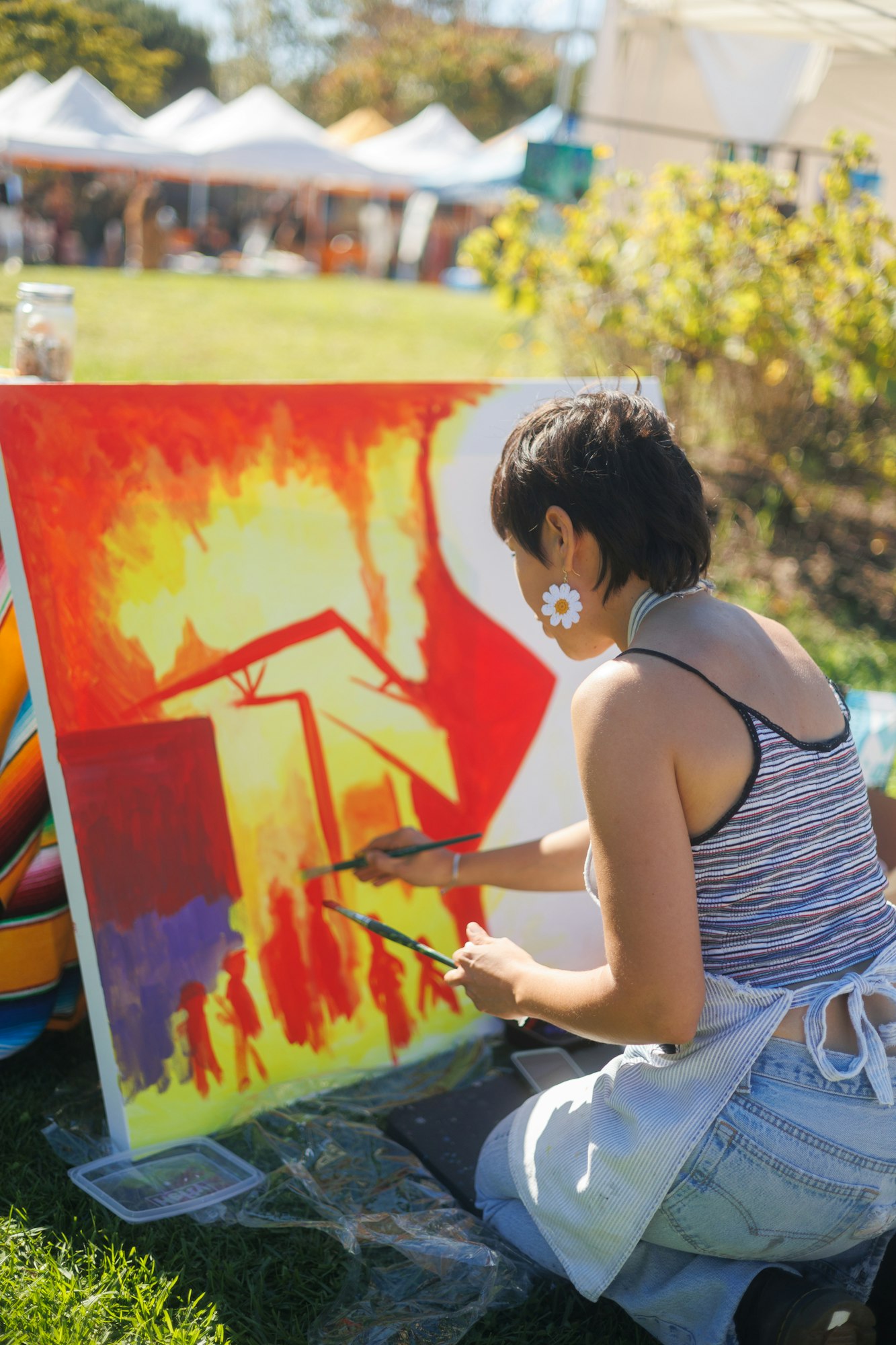 Artist painting a colorful canvas outdoors.