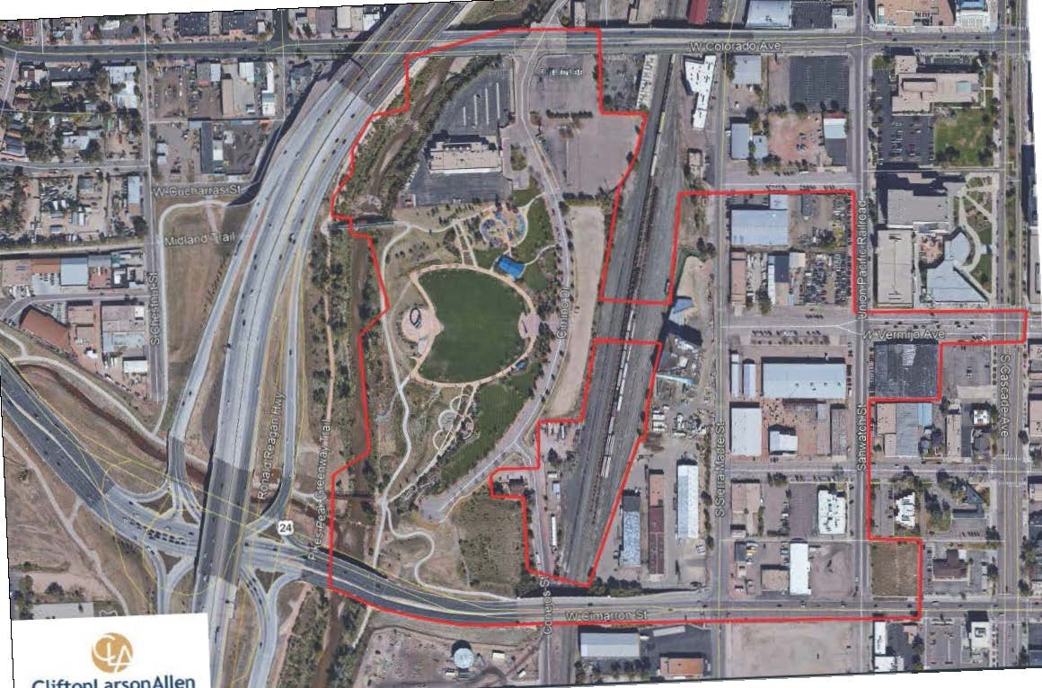 Aerial view of urban area with highways, buildings, and a park; red boundary lines outline specific sections.
