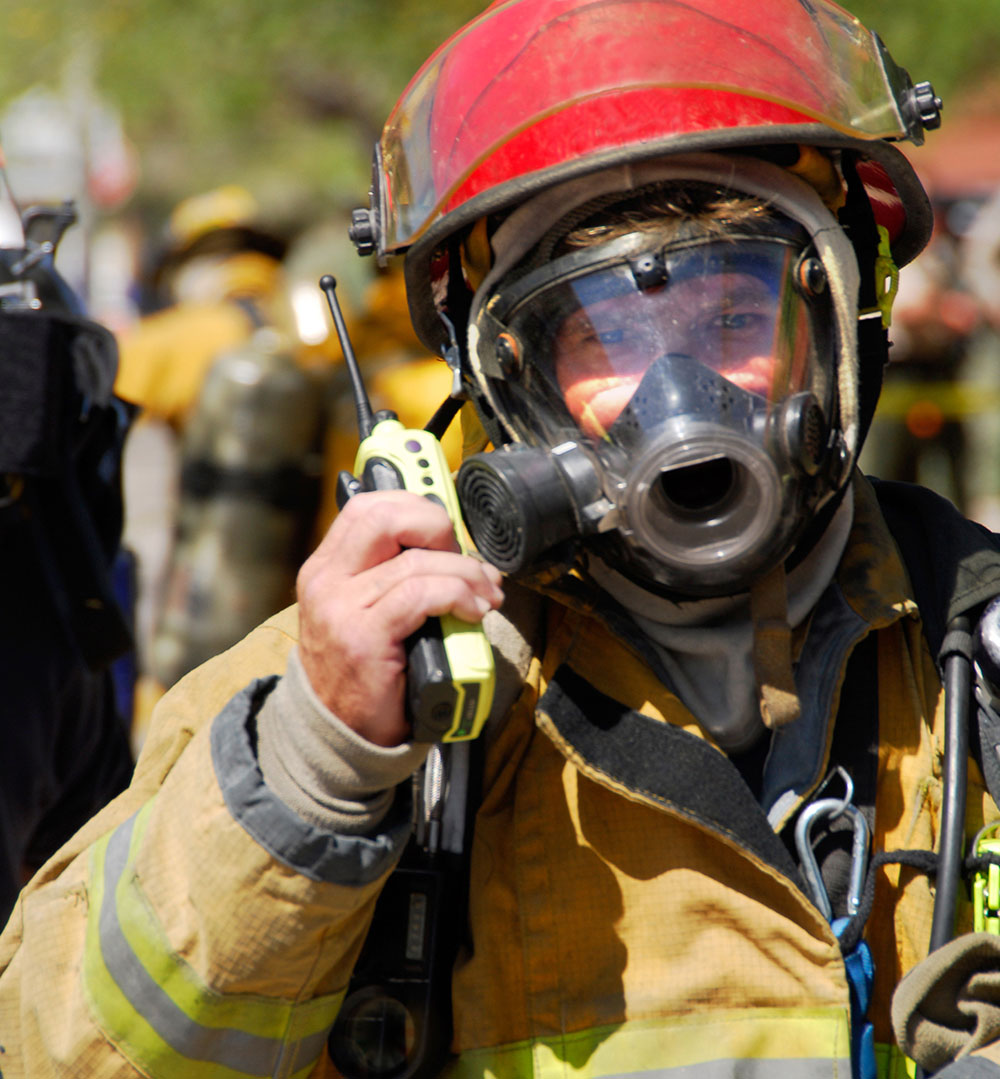 Firefighter in protective gear with a mask and a radio.