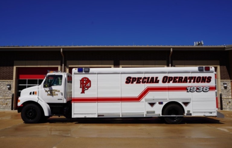 A white truck labeled "Special Operations" with red accents, parked outside a building under a clear blue sky.