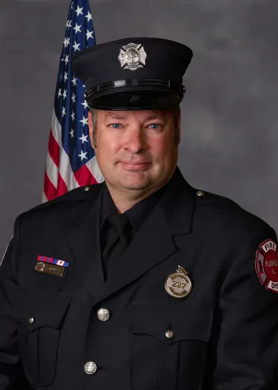 The image features a man in a firefighter uniform standing in front of an American flag.