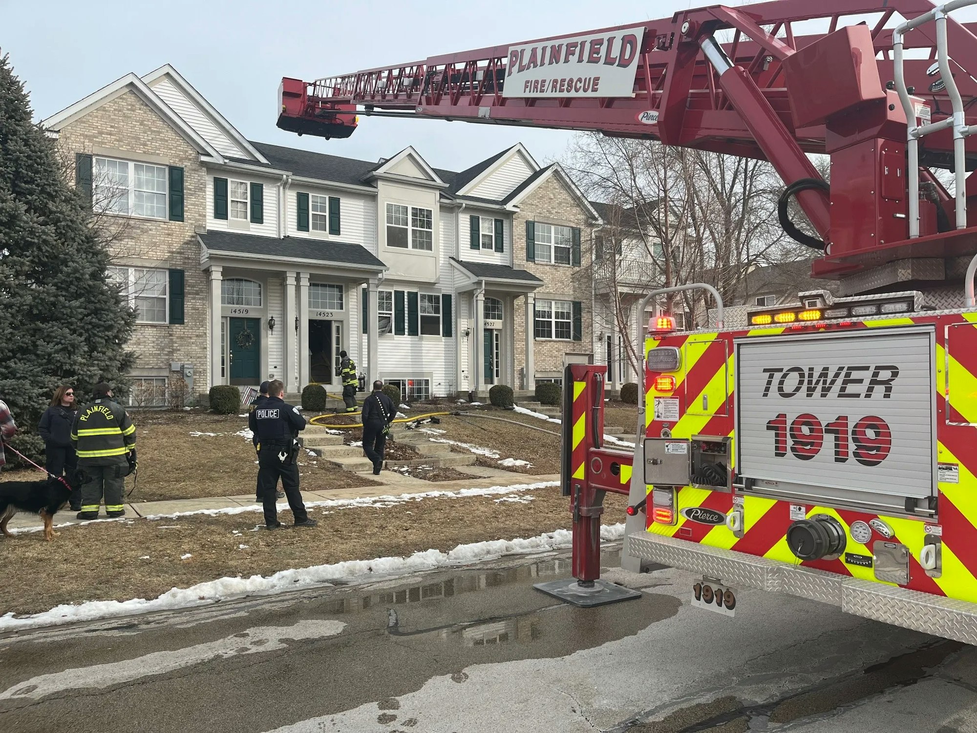 A fire truck with a ladder is at a residential scene where police and firefighters are responding to an incident.