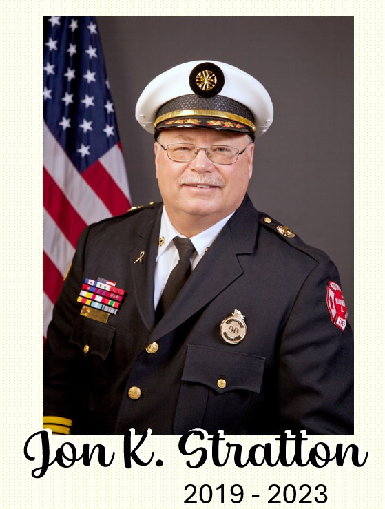 The image features a man in a uniform, likely a fire chief, with an American flag in the background and includes his name and years.