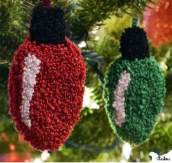 Red and green textured ornaments shaped like Christmas lights hang on a tree.