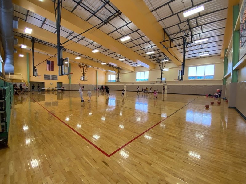Indoor basketball court with people playing and practicing.
