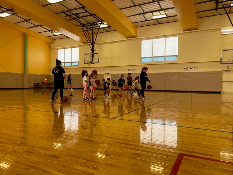 Children at a basketball practice in a gym with an instructor.