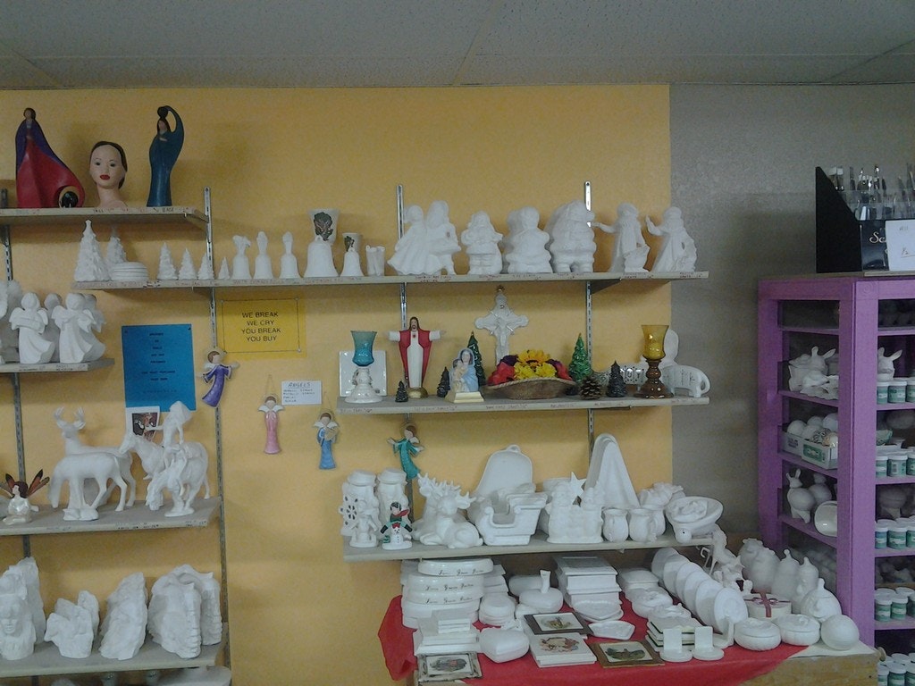 A variety of unpainted ceramics displayed on shelves, ready for crafting or painting.