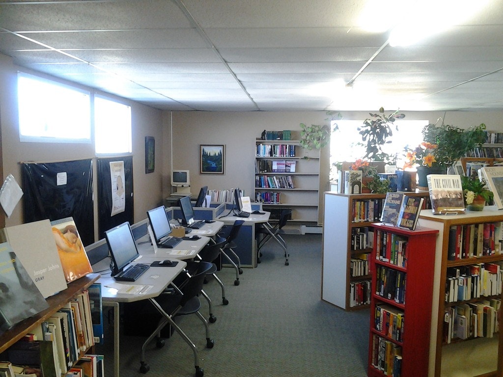 A library interior with books, computers, and plants.