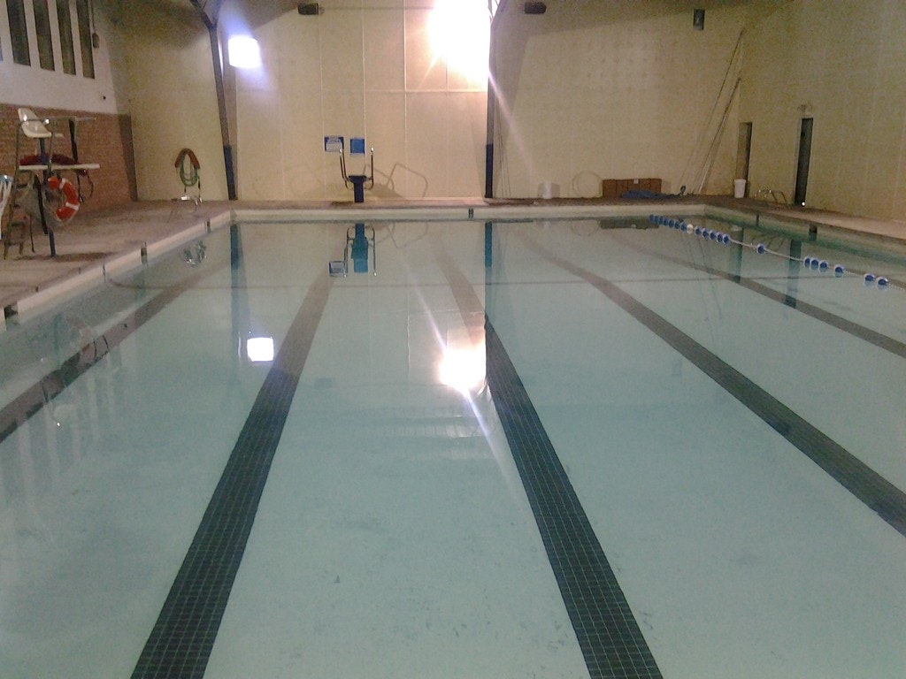 Indoor swimming pool with lanes, starting blocks, and life-saving gear on the side.