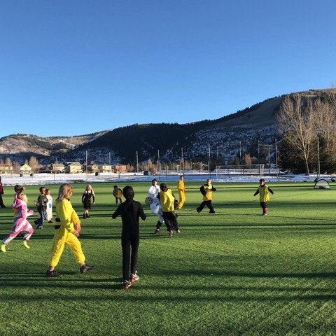 People playing sports on a field with mountains in the background.
