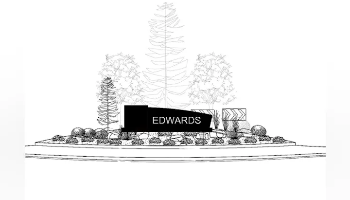 A landscaped roundabout featuring the name "EDWARDS" prominently displayed, surrounded by trees and decorative rocks.