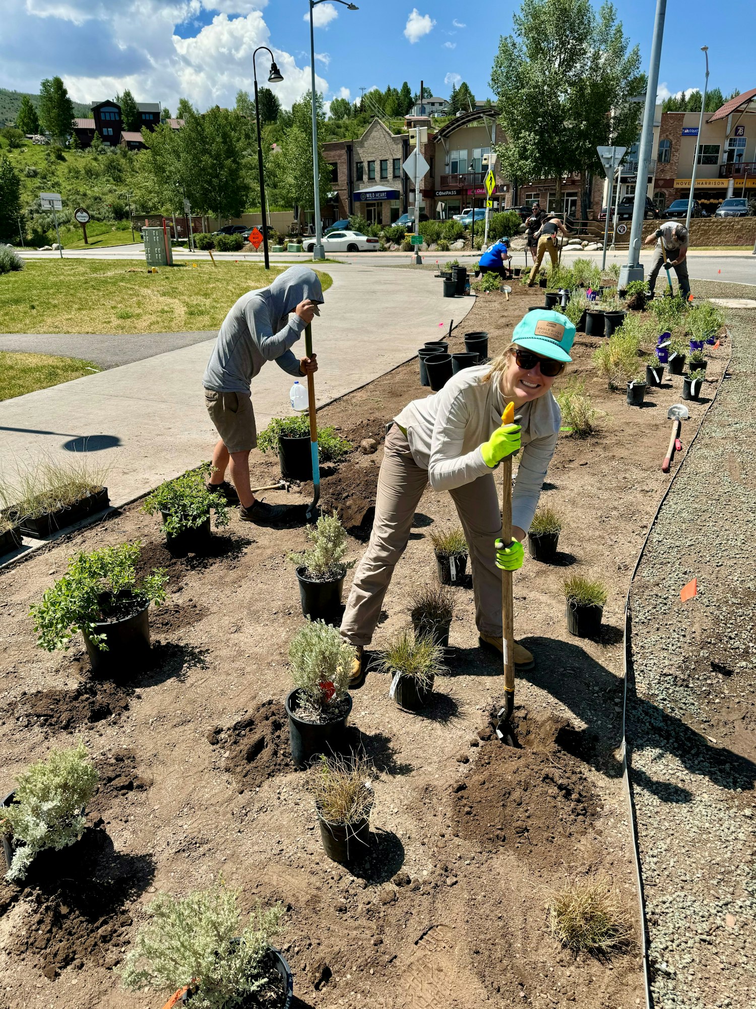 People planting in a community garden on a sunny day.
