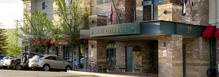 Urban street scene with cars, a bike, awning signage, and a real estate office.