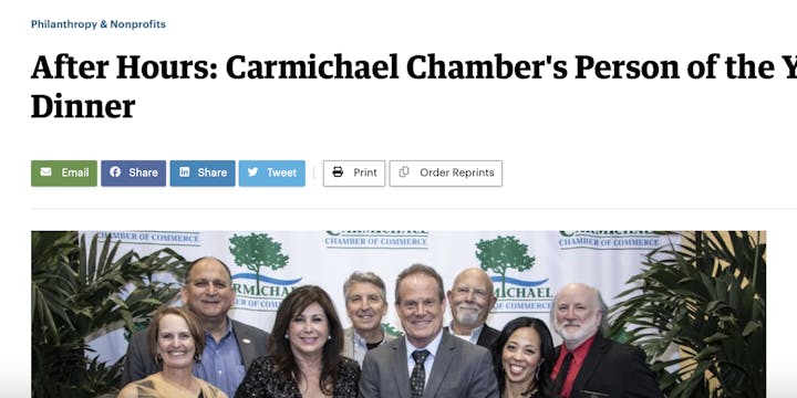Group of people posing at a "Carmichael Chamber's Person of the Year Dinner" event with a banner in the background.
