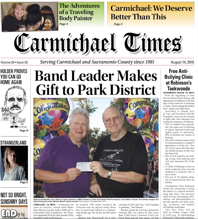 Newspaper front page with two men holding a check and various article headlines.