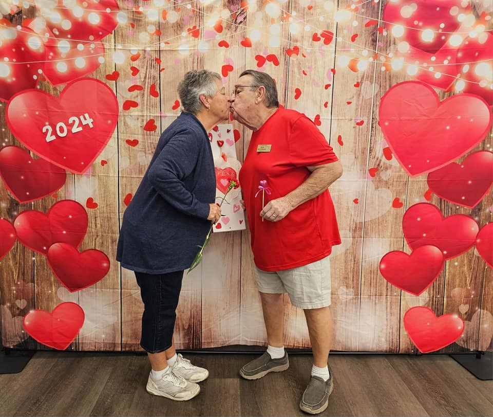 Two people kissing, surrounded by heart decorations with "2024" on a heart, Valentine's Day vibe.