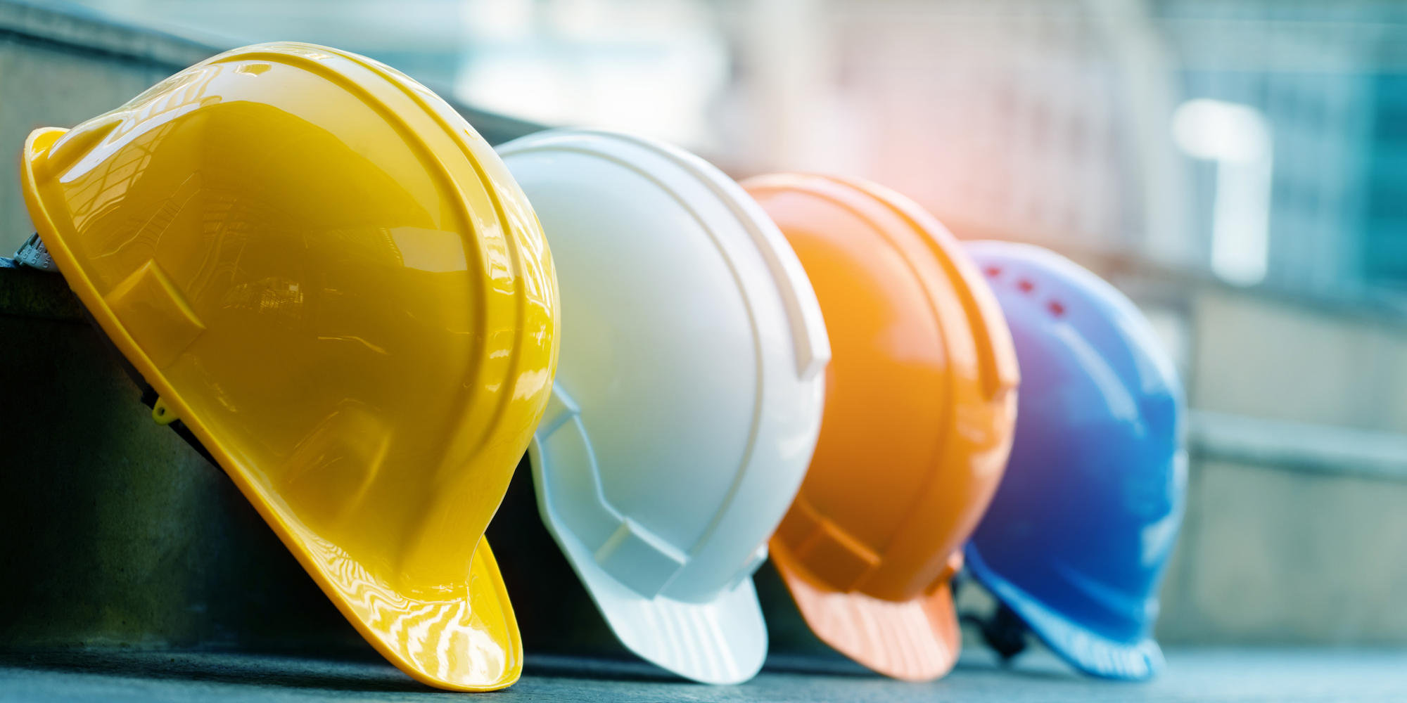 The image shows a row of colorful safety helmets lined up on a surface, likely for construction or safety use.
