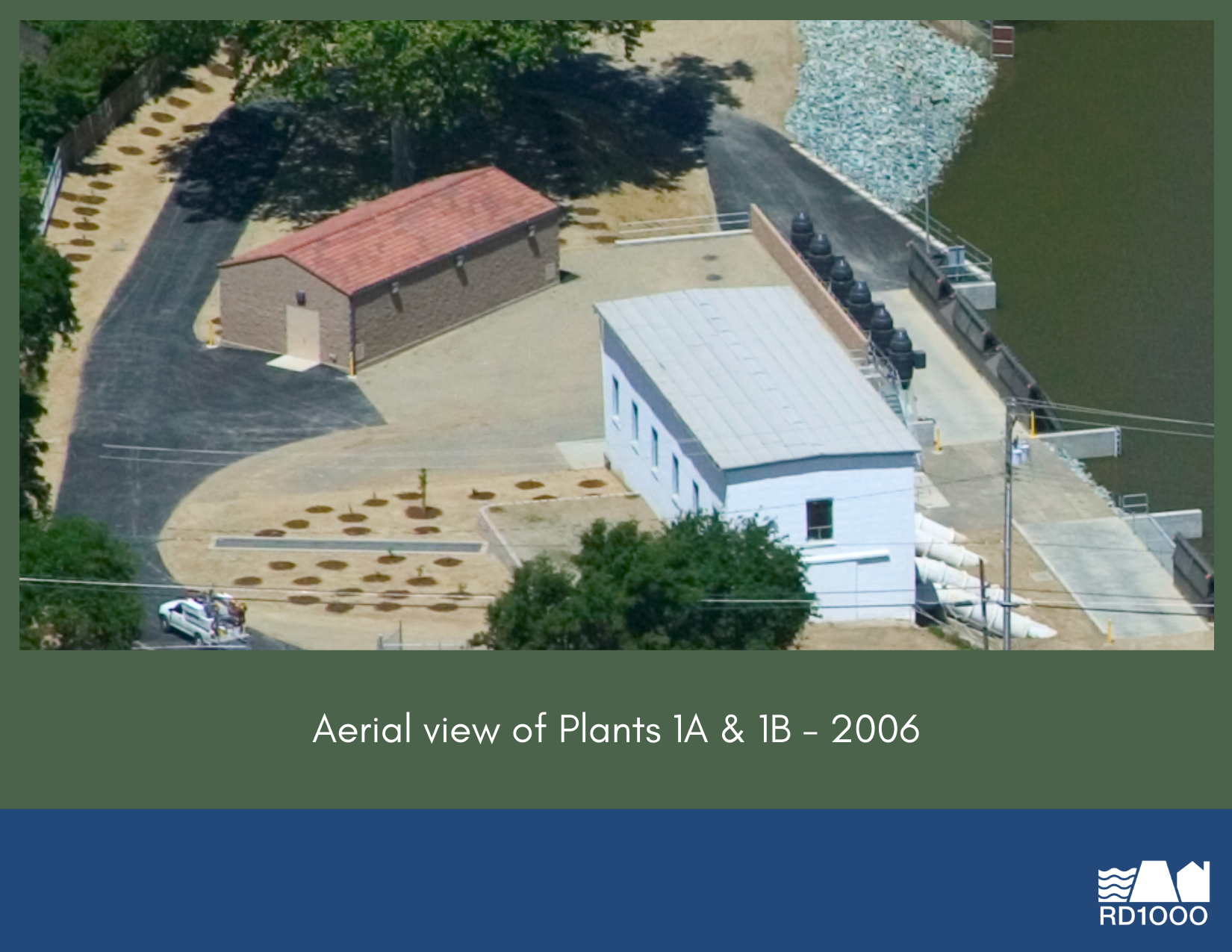 Aerial view of Plants 1A & 1B from 2006, showcasing buildings and surrounding landscape near a water body.