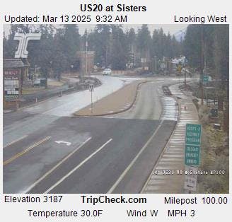 A road view from US20 at Sisters, showing an intersection, signs, trees, and a clear sky with details like temperature and wind speed.