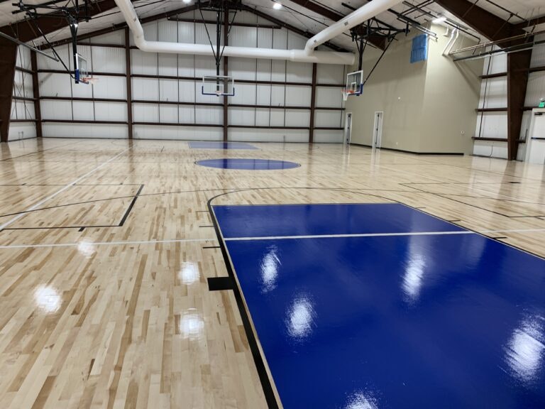 Indoor basketball court with polished wooden floor and basketball hoops.