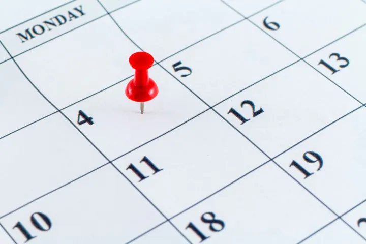 A red pushpin is marking the date "11" on a calendar, with the visible days of the week displayed.