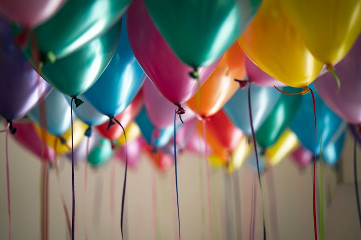 Colorful balloons with ribbons, possibly at a celebration.