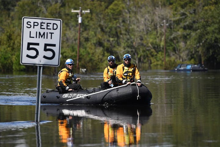 Members of Colorado Task Force 1 (CO-TF-1) conducting search and rescue operations during Hurricane Florence in a flooded area with a "Speed Limit 55" sign partially submerged.