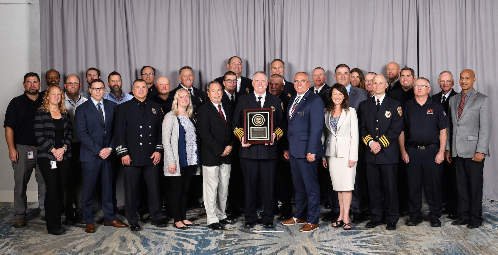 Picture shows West Metro command staff and employees, holding district's accreditation award.