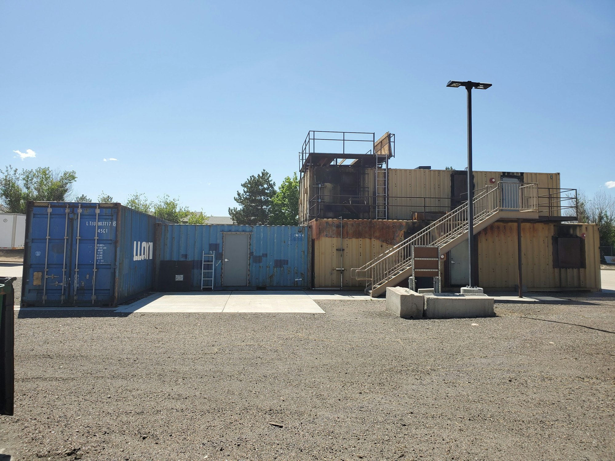 Shipping containers arranged to form a structure with stairs and railings, under a clear sky.