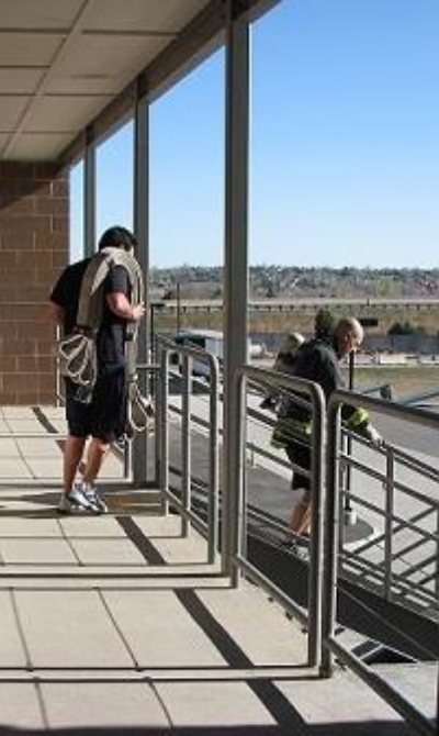 Two people climbing stairs outdoors; one carries a rope.
