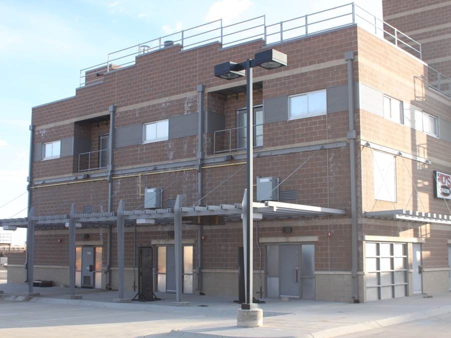 A brick building with metal stairs, several doors, air conditioning units, and an "EXIT" sign.