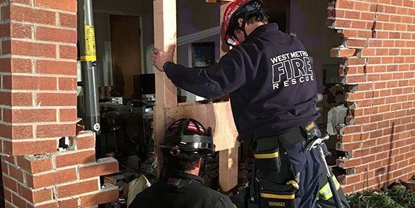 Firefighters shoring up a collapsing brick wall